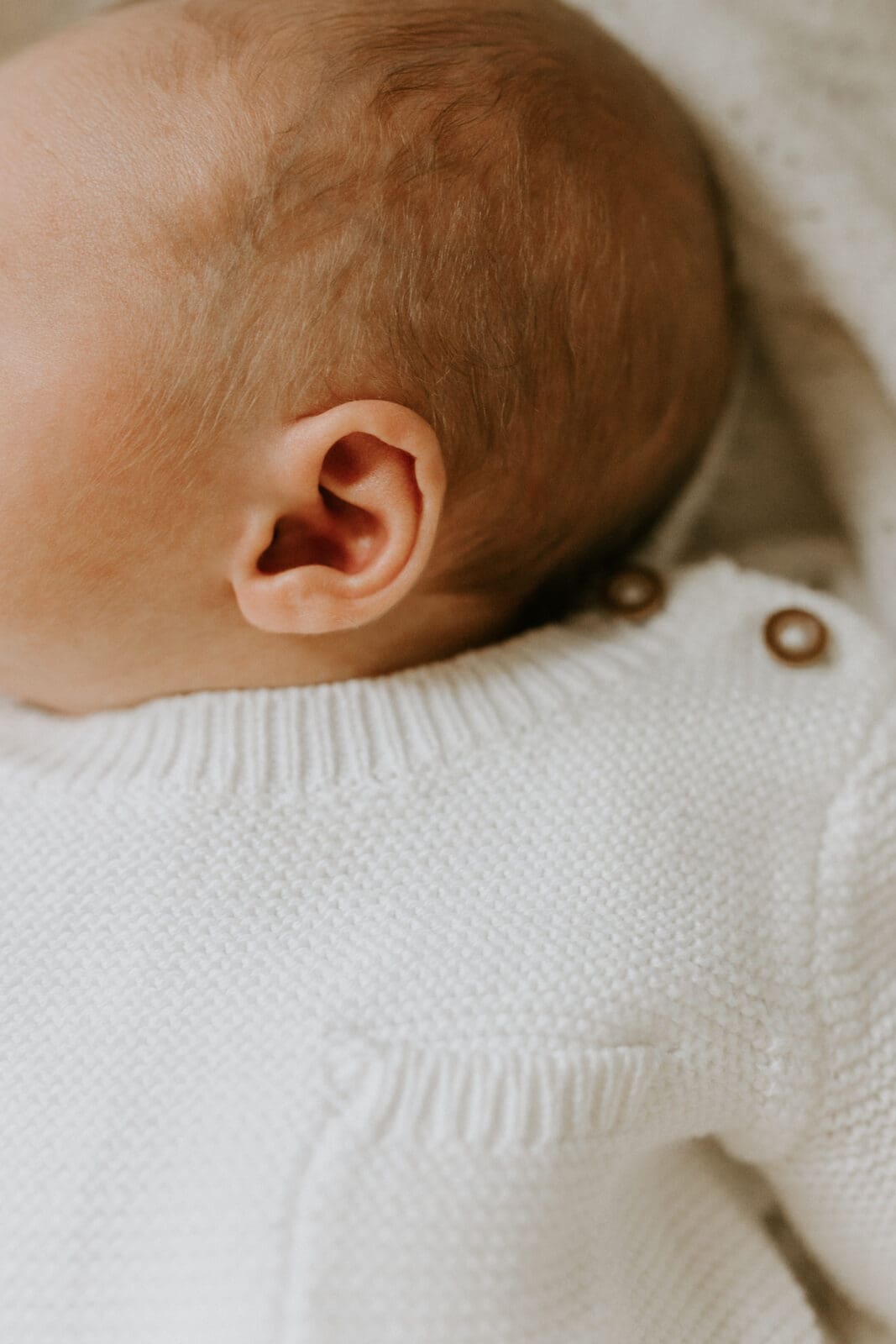 A detail photo of a baby's ear in this lifestyle newborn photography session in Lafayette, Indiana.