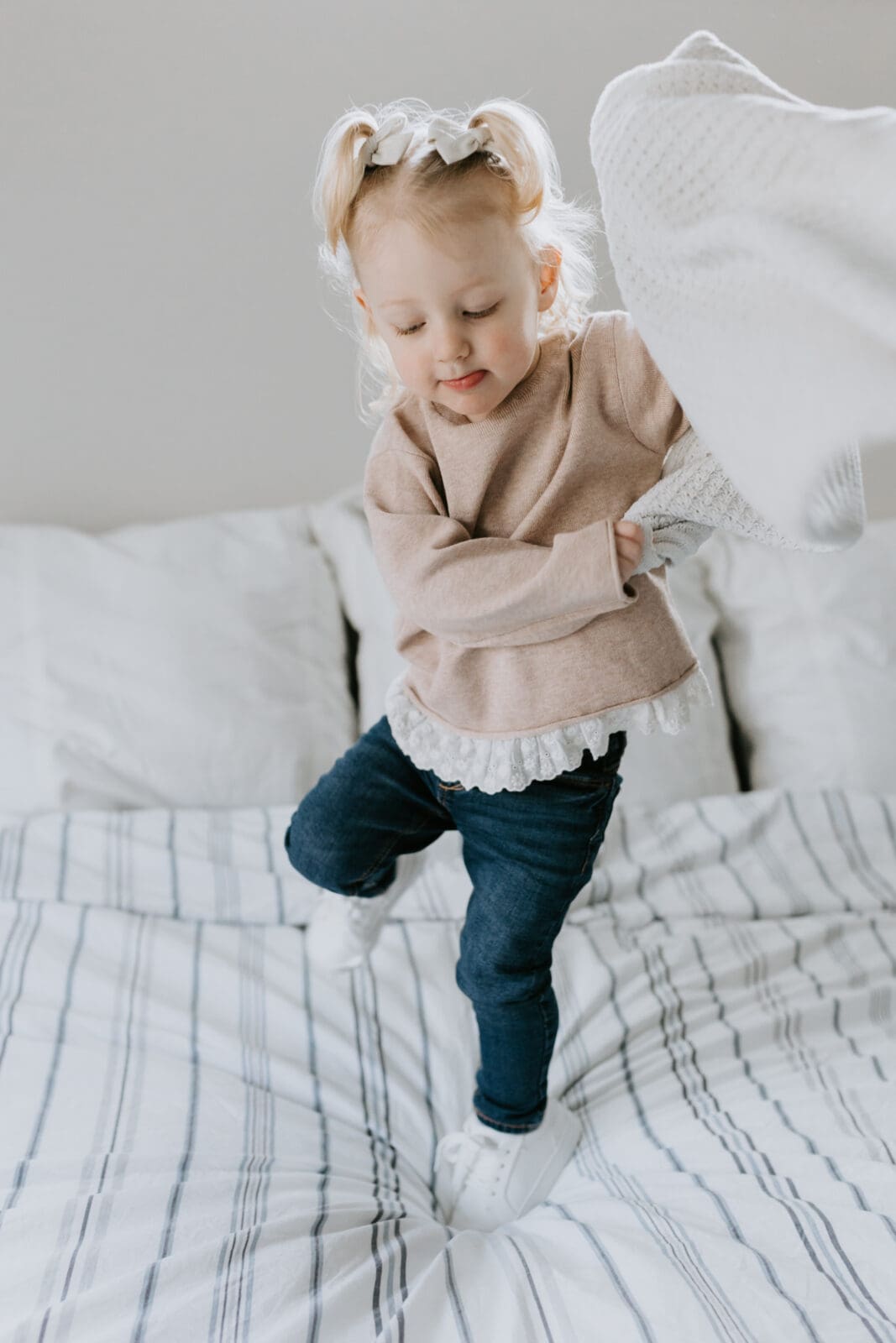 A toddler jumps on the bed.