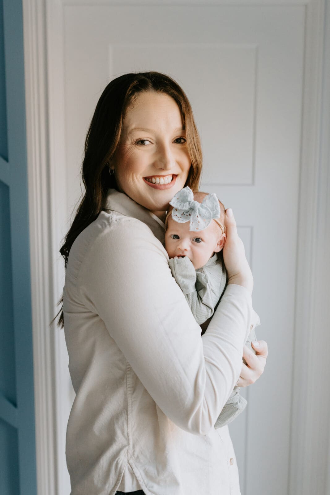 A mom holds her newborn baby close to her shoulder and smiles during this Lafayette, Indiana newborn photo shoot.