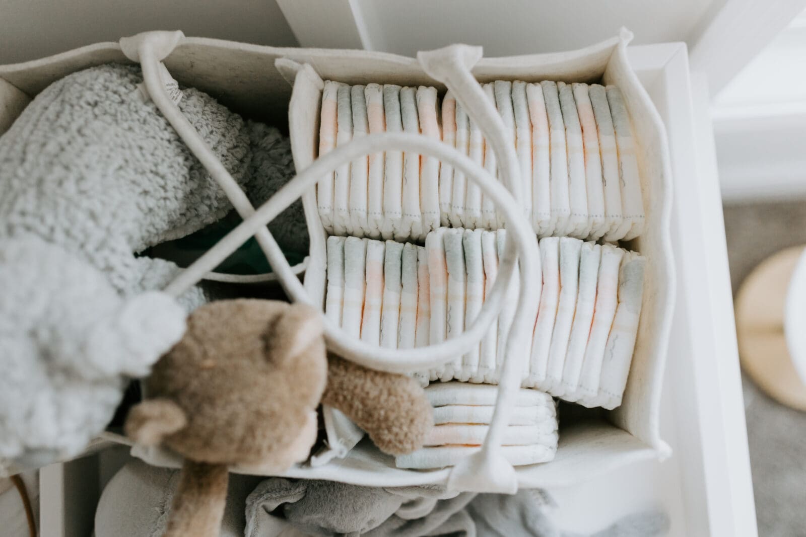 A close up photo of diapers and stuffed animals in a diaper changing caddy.