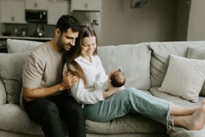 mom and dad hold their newborn on the sofa