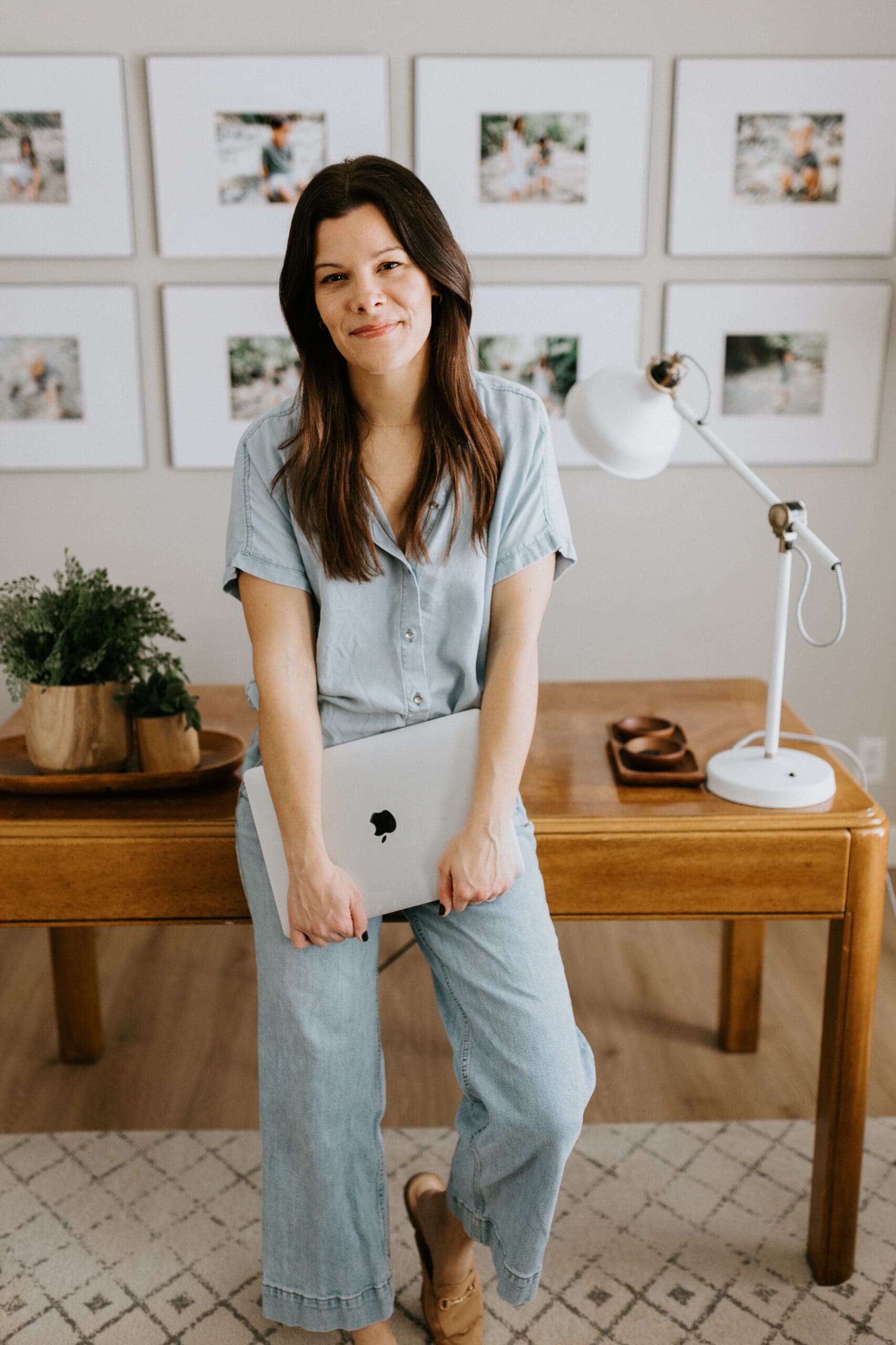Photographer Vanessa Stoller holds her laptop while standing in front of her home office desk in West Lafayette, Indiana.