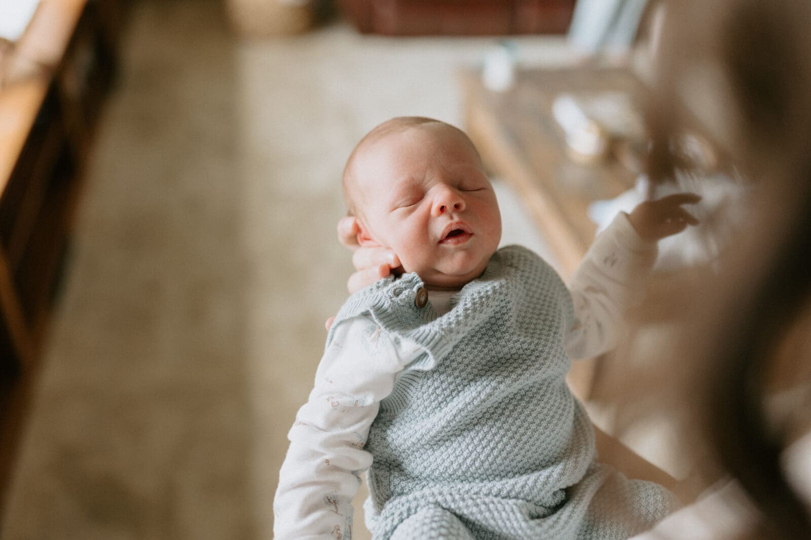 A view from above of a mom cradling a newborn baby boy's head in her hands. The baby is sleeping for this newborn photography session with Vanessa Stoller.
