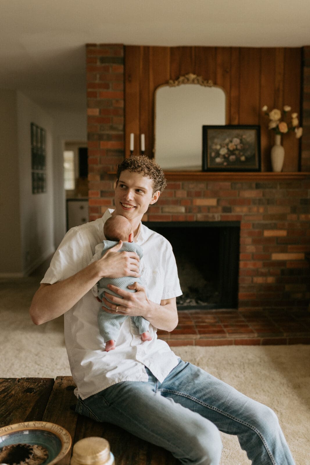 A new dad smiles over his shoulder as he holds his fussy newborn baby boy to his shoulder.