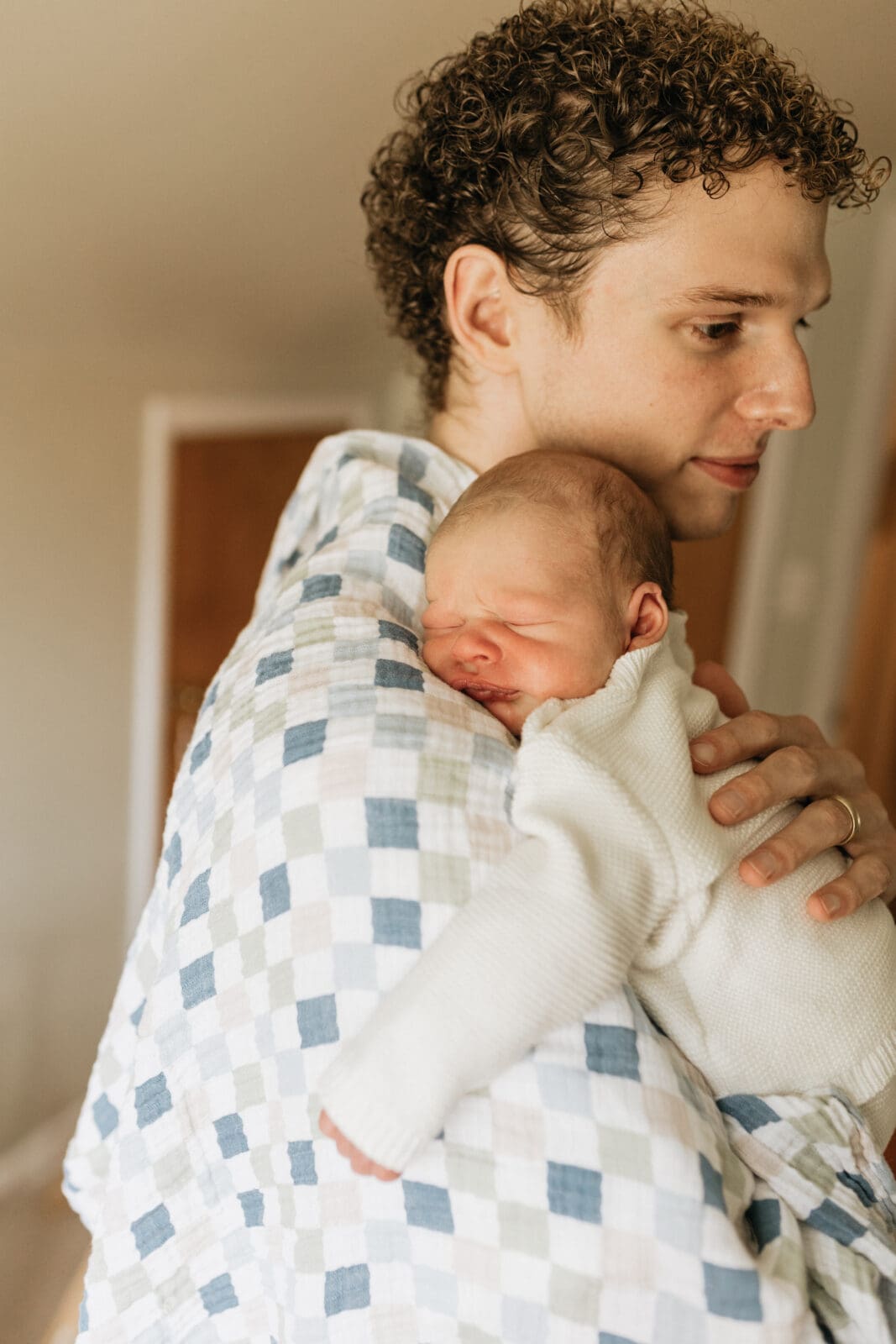 A new dad comforts his baby by holding him close to his shoulder and patting him on the back.