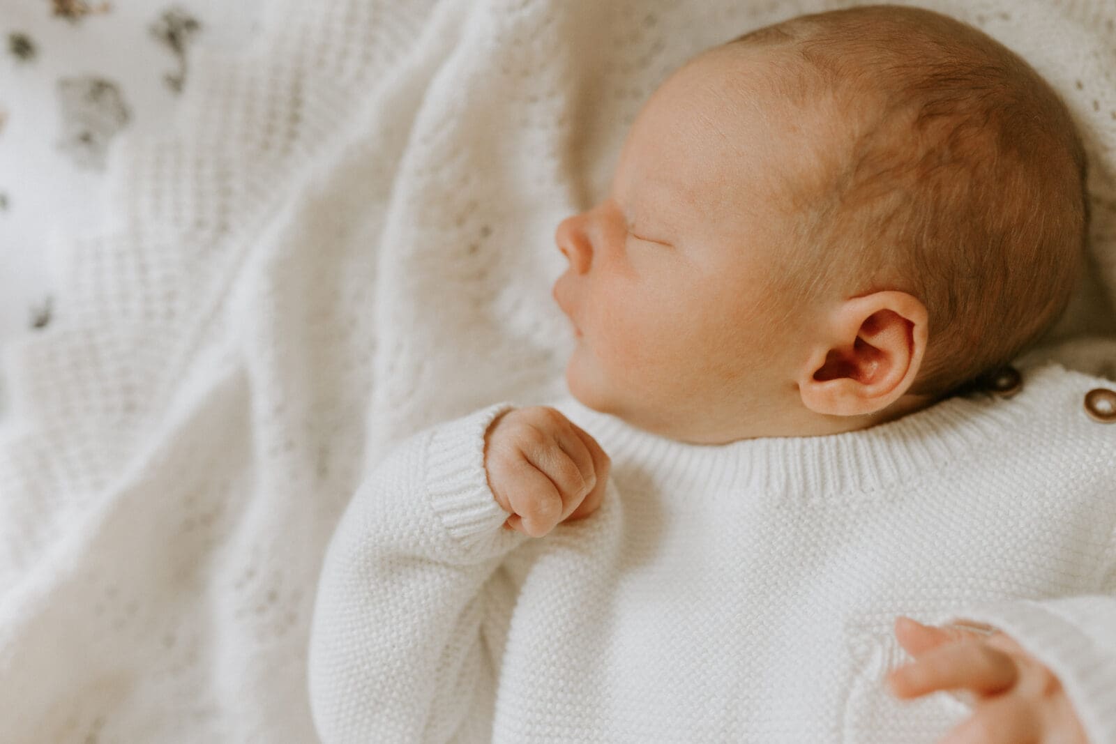 A profile view of a baby sleeping in his bed.