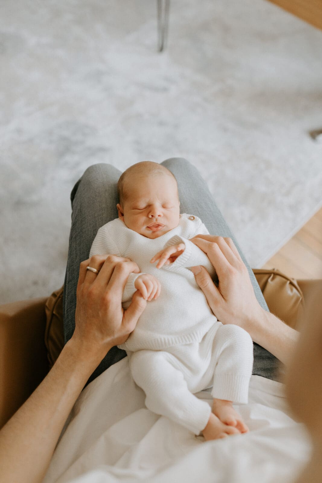 The camera perspective is from above as a new baby sleeps in his father's lap.