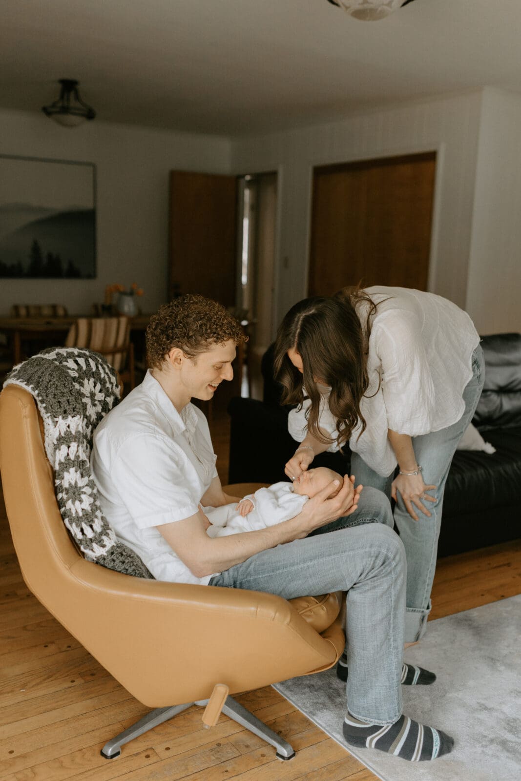 A new mom and dad smile down at their baby boy in their midcentury West Lafayette home.