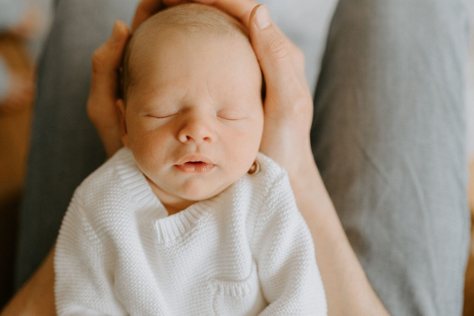 A close up of a newborn baby being cradled by his dad's arms.