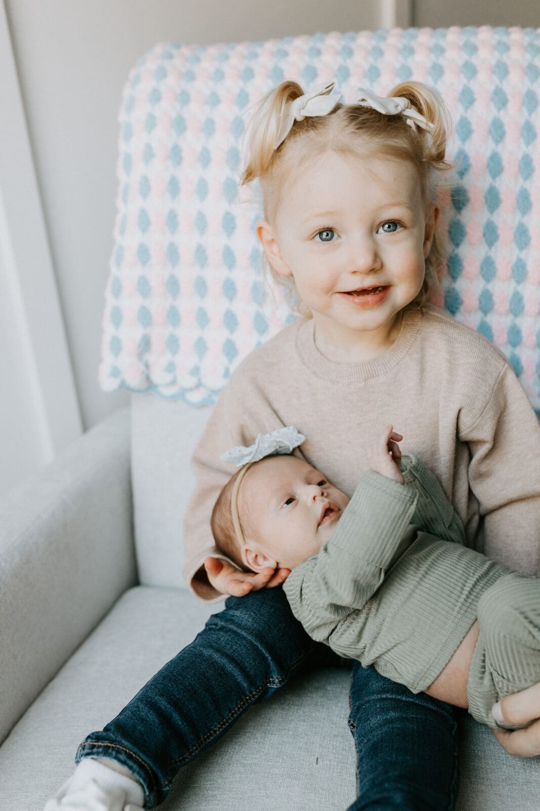 A portrait of a toddler holding her baby sister during a Lafayette, Indiana newborn photography session.