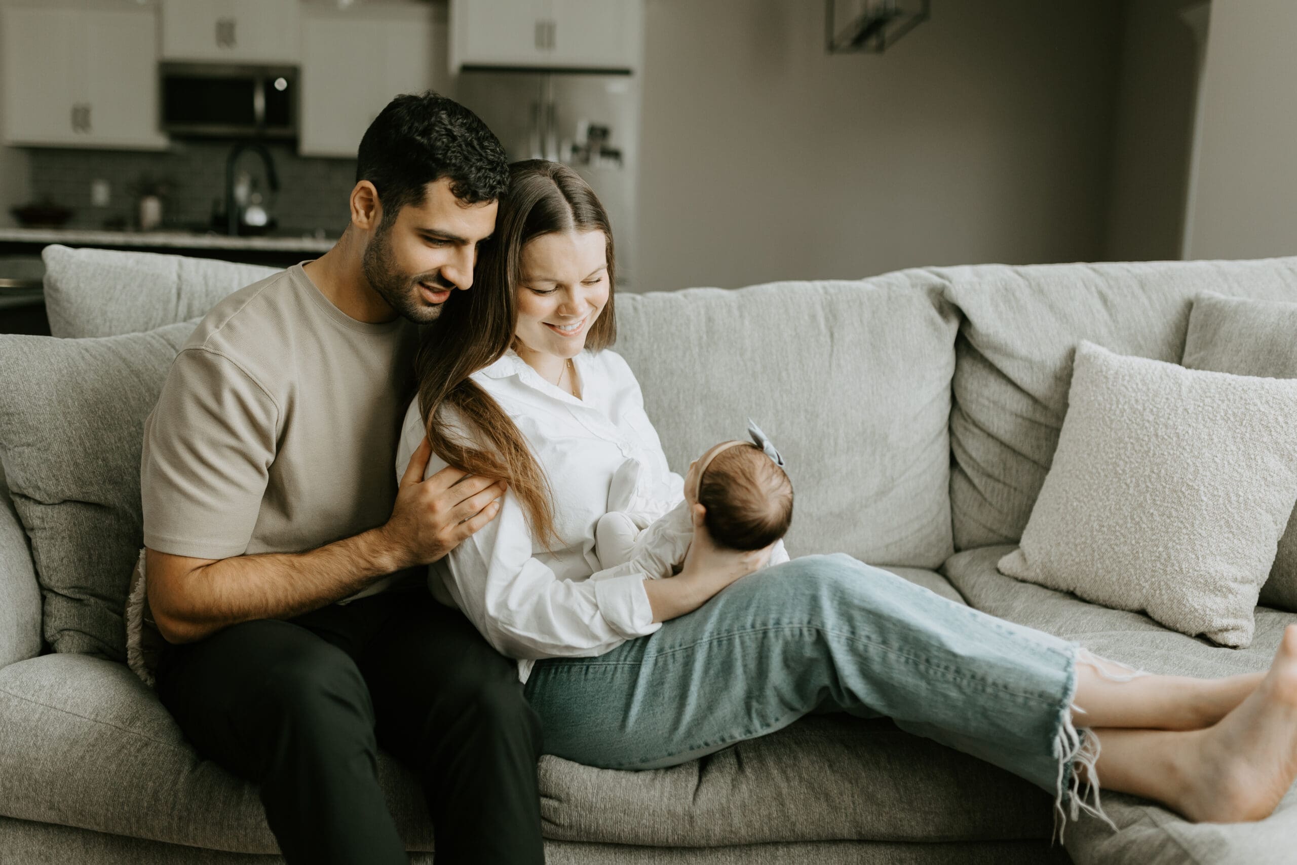 mom and dad hold their newborn on the sofa