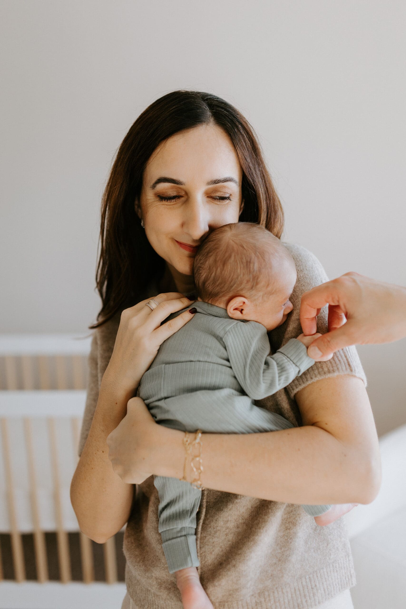 A mom holds her baby close to her chest and smiles.